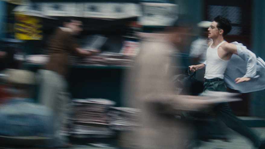 Mies juoksee kiireisen näköisenä kadulla.