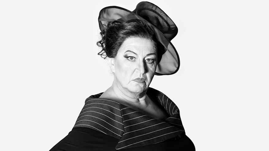 Tuima nainen katsoo kameraan hattu päässä.