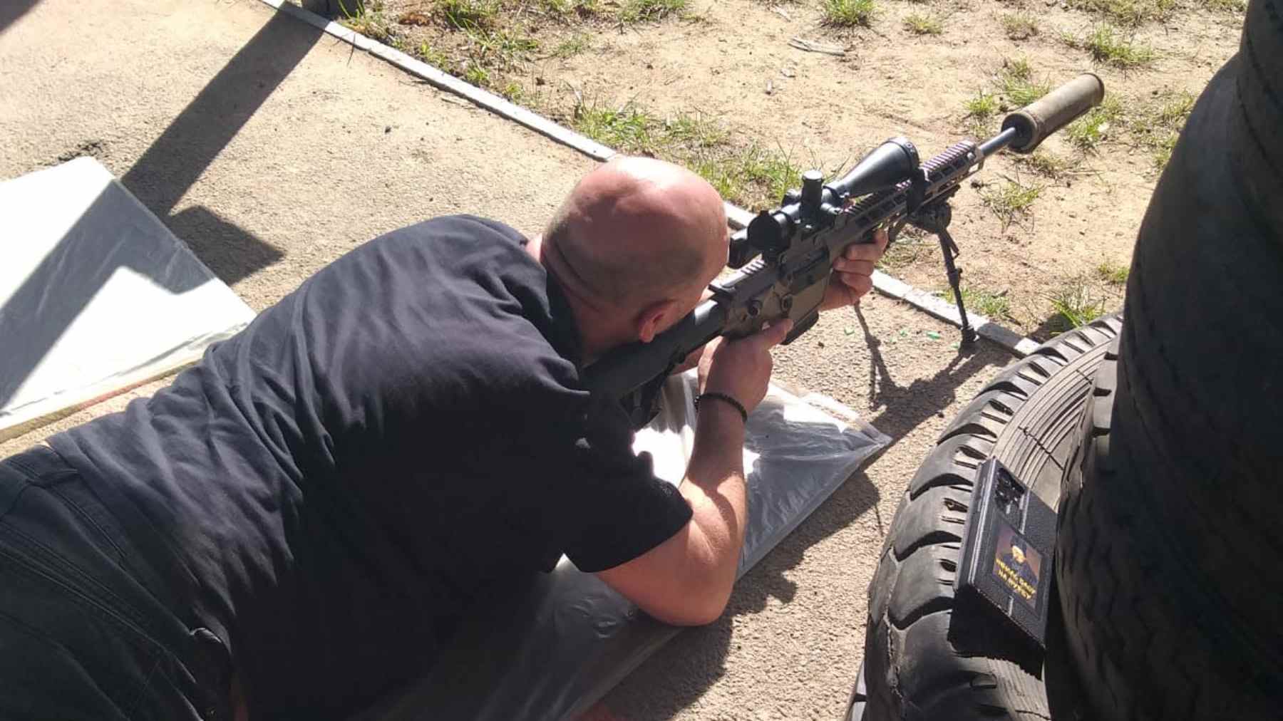 Mies ampuu makuullaan konetuliaseella ukrainalaisella ampumaradalla.