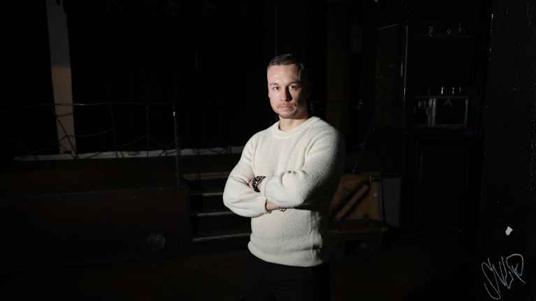 Mies valkoisessa paidassa katsoo kameraan.