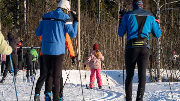 Hiihtäjiä ladulla metsän läheisyydessä.
