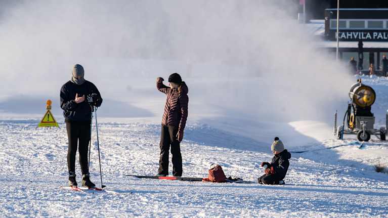 Ulkoilijoita latukoneen lähellä.