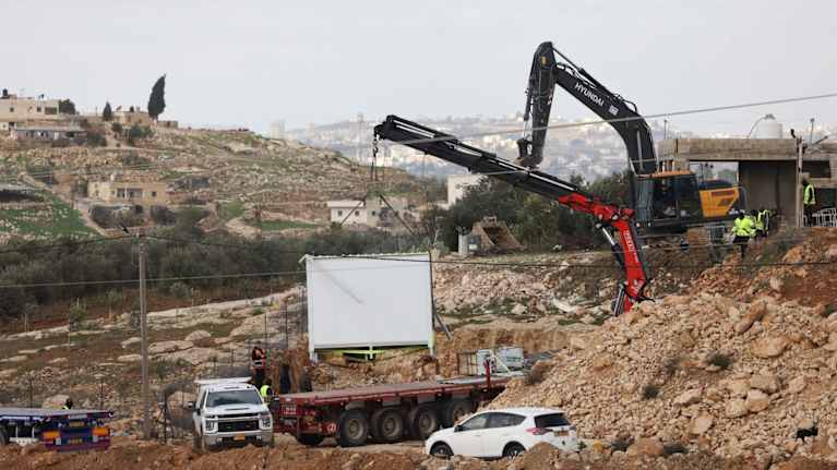 Rakennusmiehet purkavat rakennuksia joutomaalla Länsirannalla. Töihin käytetään kaivinkoneita.