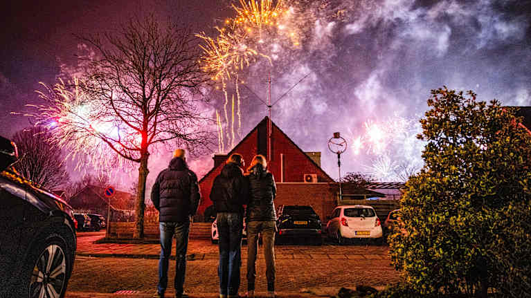 Ihmiset seuraamassa ilotulitusta asuinalueella.