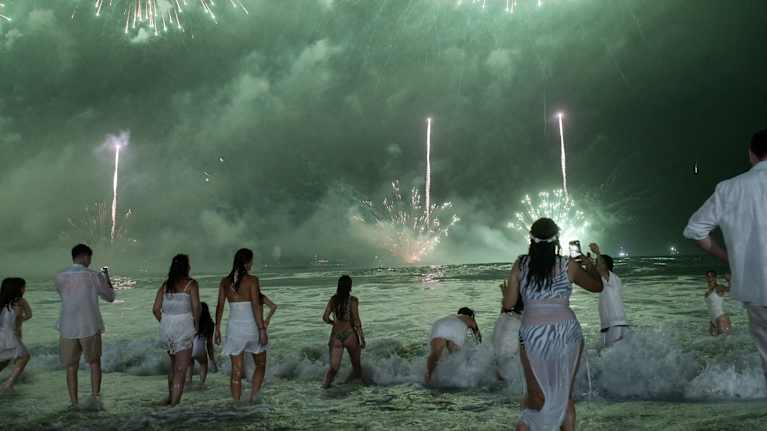 Ihmisia juhlimassa rannalla.