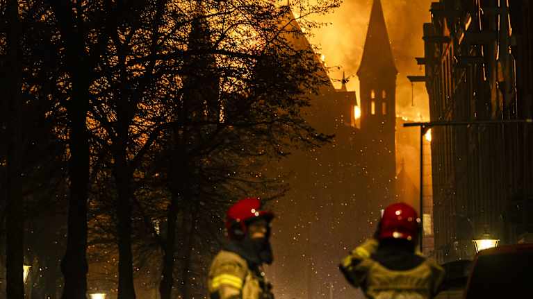 Palomiehiä palavan kirkon edessä.