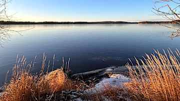 Järvimaisema, jonka etualalla on kalliota ja heinikkoa.