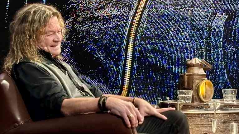 Jussi Aaltonen istuu penkillä ja hymyilee.