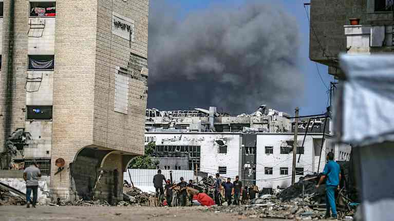 Savu nousee taivaalle rakennusten takana.