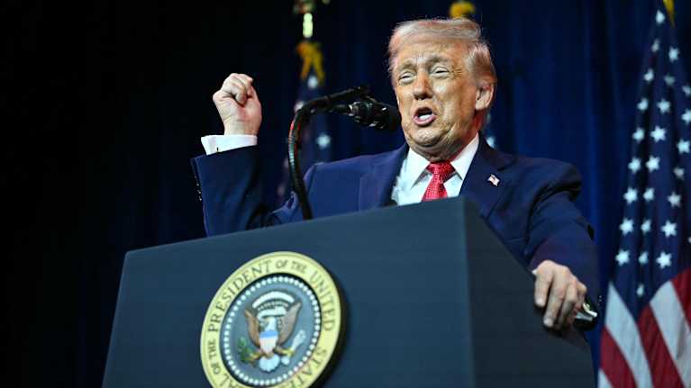 Donald Trump puhuu puhujankorokkeella mikrofoniin.