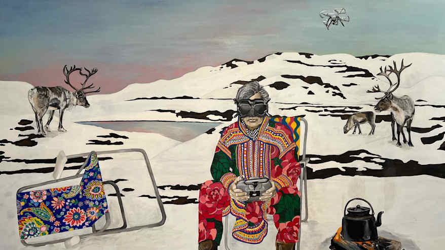 Mies istuu tuolilla päällään värikäs saamenpuku. Vieressä on nuotiolla kahvipannu.