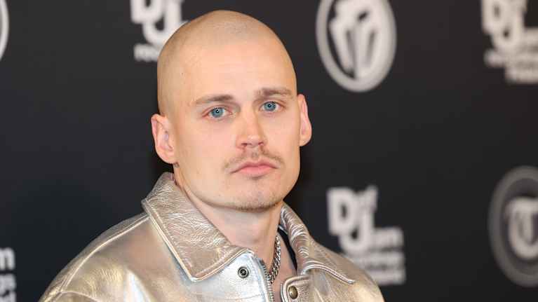 Rap-artisti Gettomasa henkilökuvassa. Hän katsoo suoraan kameraan, yllään hopean värinen nahkatakki. 