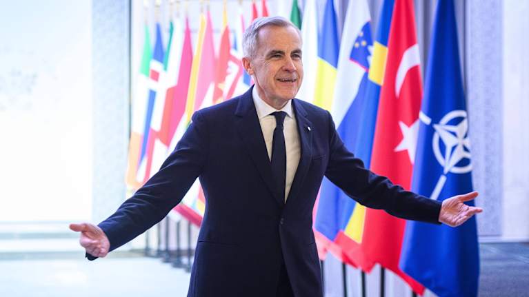 Mies levittää käsiään lippuriviston edessä.