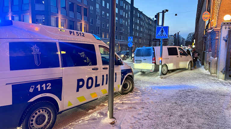 Poliisin ajoneuvoja osin jalkakäytävälle pysäköityneenä Tampereella, taustalla kerrostalo ja liikennettä.