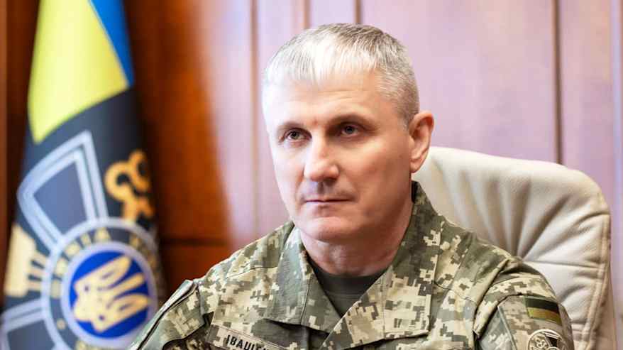 Maastoasuun pukeutunut henkilö istuu päydän äärellä.