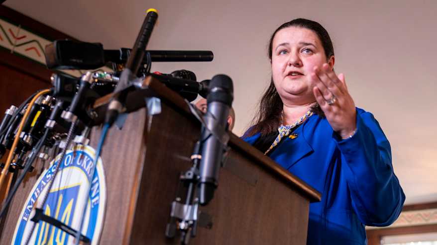 Henkilö seisoo puhujapöntön takana tiedotustilaisuudessa.