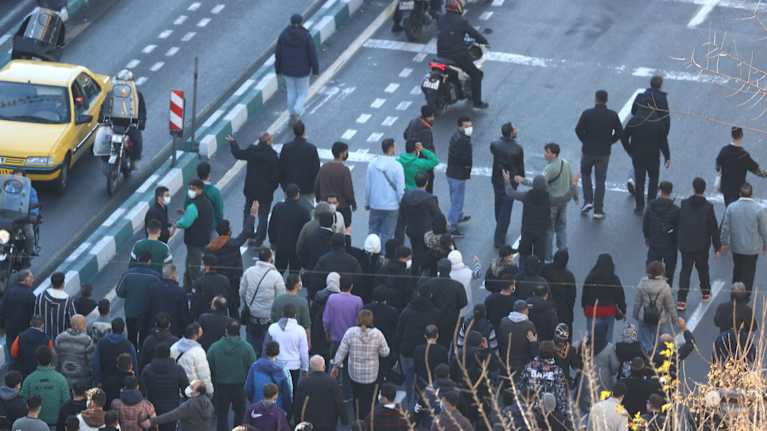 Talvivaatteisiin pukeutuneita ihmisiä marssii kadulla Teheranissa, Iranissa.