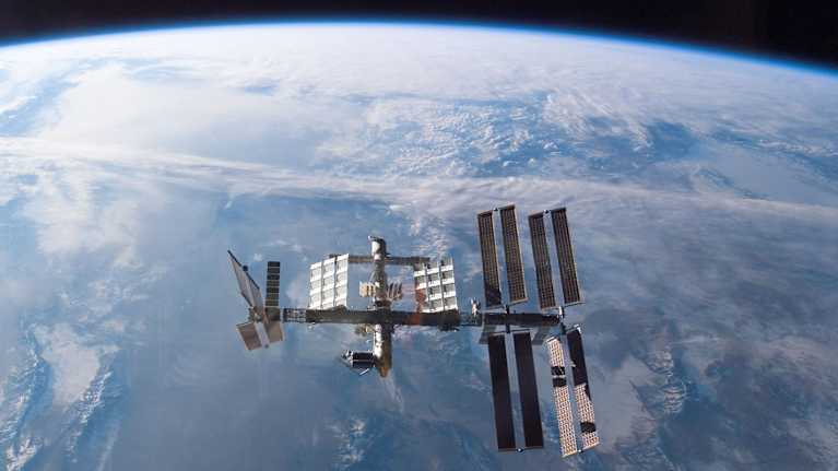 Kansainvälinen ISS-avaruusasema avaruudessa, taustalla maapallon pintaa.