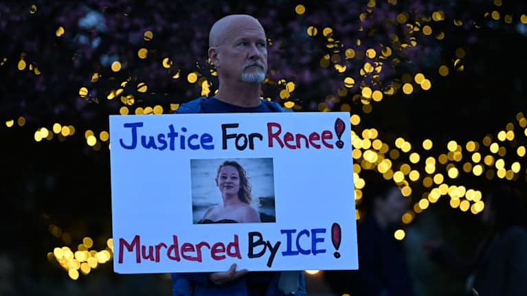Henkilö pitelee banderollia, jossa on Renee Nicole Goodin kuva ja teksti "Justice for Renee! Murdered by ICE!"
