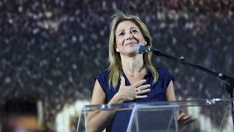 Maria Karystianou puhujapöntössä, katsoo yläviistoon ja pitää kättä rinnallaan. 