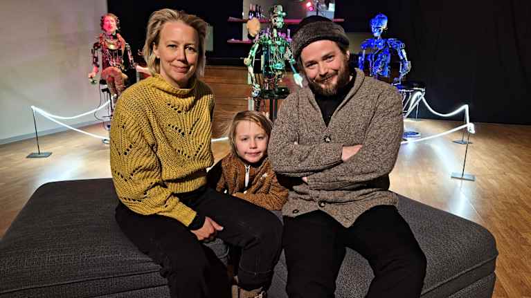 Teija, Iisakki ja Pekka Isorättyät istuvat. Taustalla robotteja.