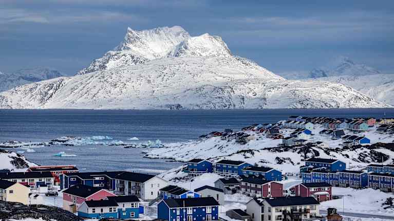 Etualalla on erivärisiä taloja. Taustalla on luminen vuori.