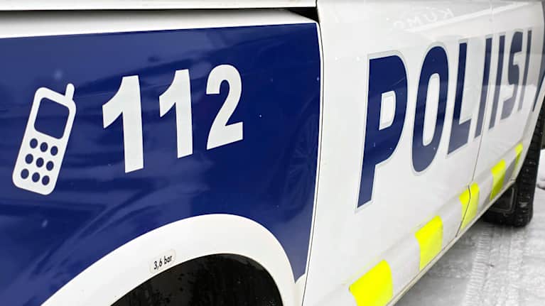Poliisiauton kyljessä oleva poliisi teksti ja numerot: "112" sekä symboli, joka edustaa puhelinta.