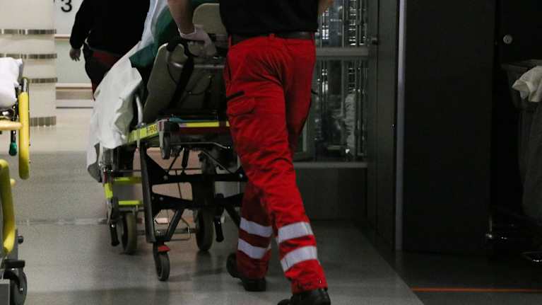 Ensihoidon työntekijä kuljettaa potilasta sairaalan käytävällä.