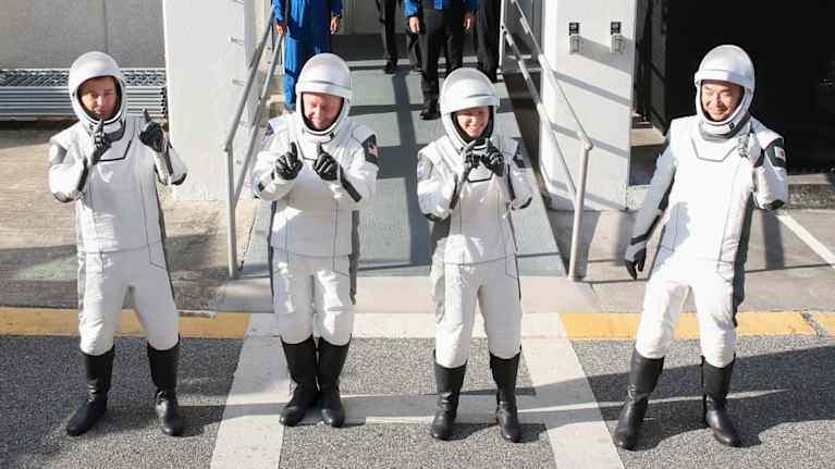 Neljä astronauttia seisoo rivissä ja poseeraa kameroille avaruuskeskuksen ulkopuolella.