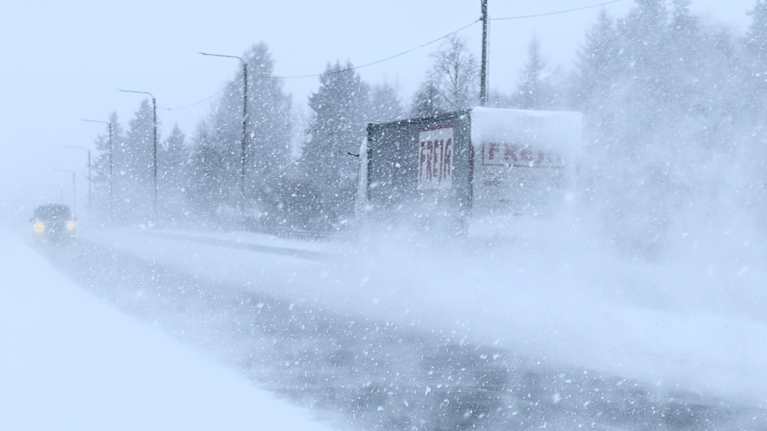 Rekka ajaa sankassa lumipyryssä maantiellä, henkilöauto tulee vastaan omalla kaistallaan.