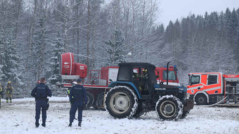 Mustunut traktori lumisessa maisemassa.