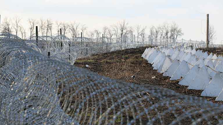Piikkilanka-aitaa ja betoniesteitä.