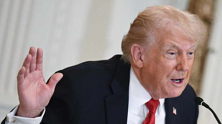 Trump puhuu mikkiin ja viittilöi kädellään.