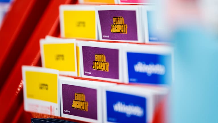 Veikkauksen pelilomakkeita punaisessa telineessä.