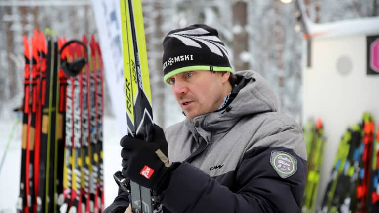 CustomSkin toimitusjohtaja Esa Vironen pitelee suksiparia käsissään.