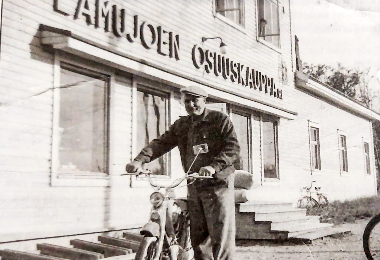 Kalle Hankonen mopoineen kaksikerroksiseksi muutetun Lamujoen Osuuskaupan Piippolan myymälän edessä 1950-60-lukujen taitteessa.