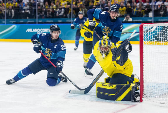 Suomalainen jääkiekonpelaaja laukoo Ruotsin maalia kohti.