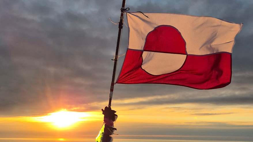 Grönlannin lippu tangossa vuoren huipulla.