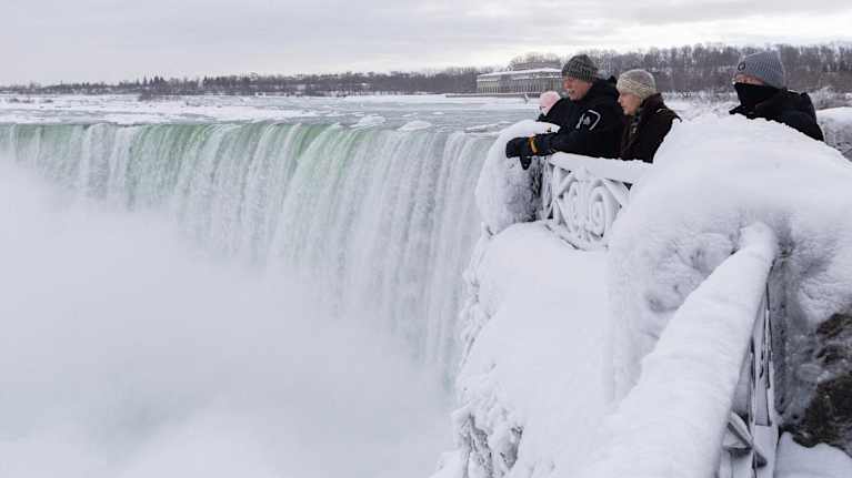 Ihmisiä katsomassa jäistä vesiputousta.