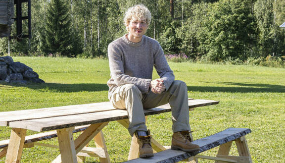Janne Naakka istuu pöydällä.
