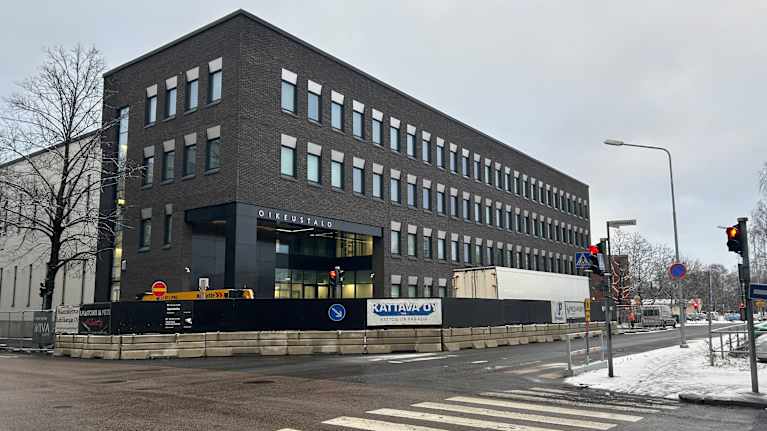 Rakennusaitojen takana, uusi viimeistelyvaiheessa oleva ruskeatiilinen Porin uusi oikeustalo.