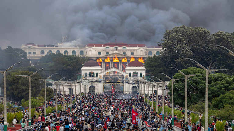 Nepalin hallintorakennus Singha Durbar tulessa ja mielenosoittajia edustalla paljon.