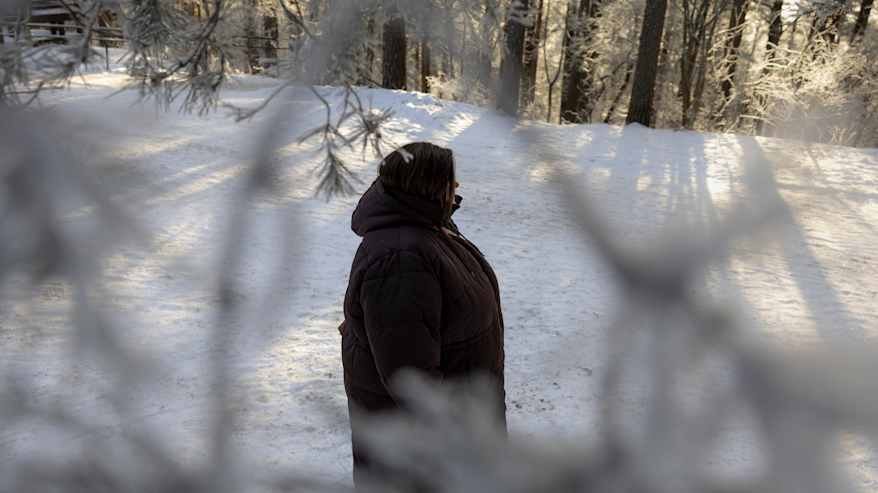 Nainen kävelee talvisella metsätiellä.