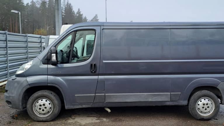 Harmaa pakettiauto parkkipaikalla.