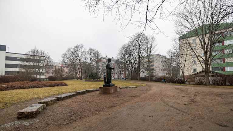 Salpapuisto Kouvolan keskustassa. Ilma on usvainen. Puistossa seisoo myös kirjailija ja toimittaja Unto Seppäsen patsas.