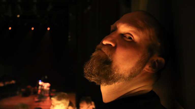 Henkilö konsertissa hämärästi valaistussa salissa.