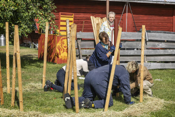 Farmi Suomen kisaajat pystyttävät aidantolppia maahan.