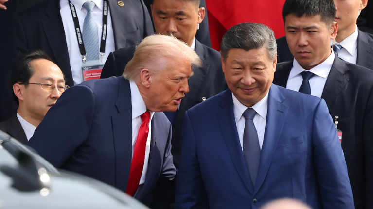 Donald Trump kumartuneena Xi Jinpingin puoleen, taustalla Xin seuruetta ja etualalla auto.