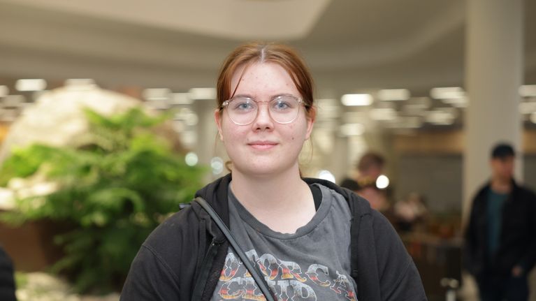 Punatukkainen silmälasipäinen nuori nainen katsoo suoraan kameraan.