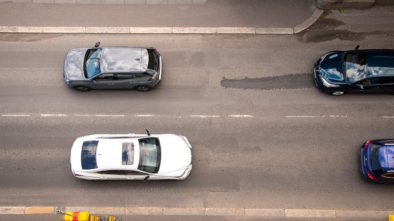 Autoja ajamassa tiellä. Kuva on otettu pystysuoraan tien yläpuolelta, niin kutsutusta lintuperspektiivistä.